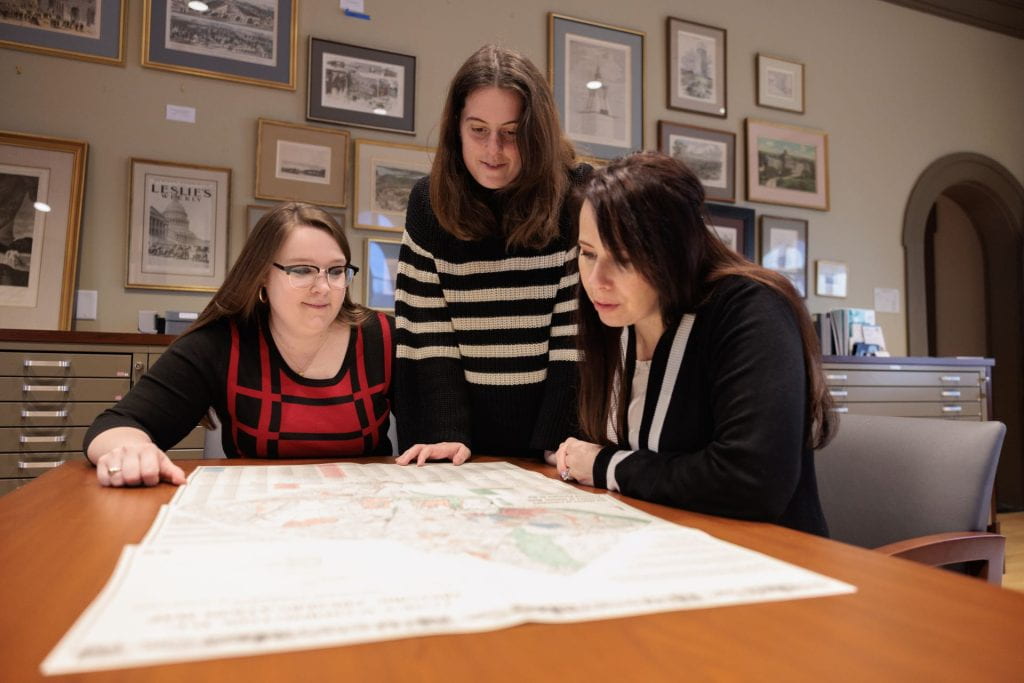 Three women gathered around a table looking at a map