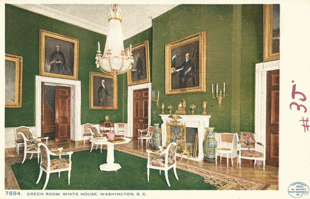 Postcard of the Green room in the White house. It has green walls and a green carpet, with white furniture and many portraits hanging on the walls. 