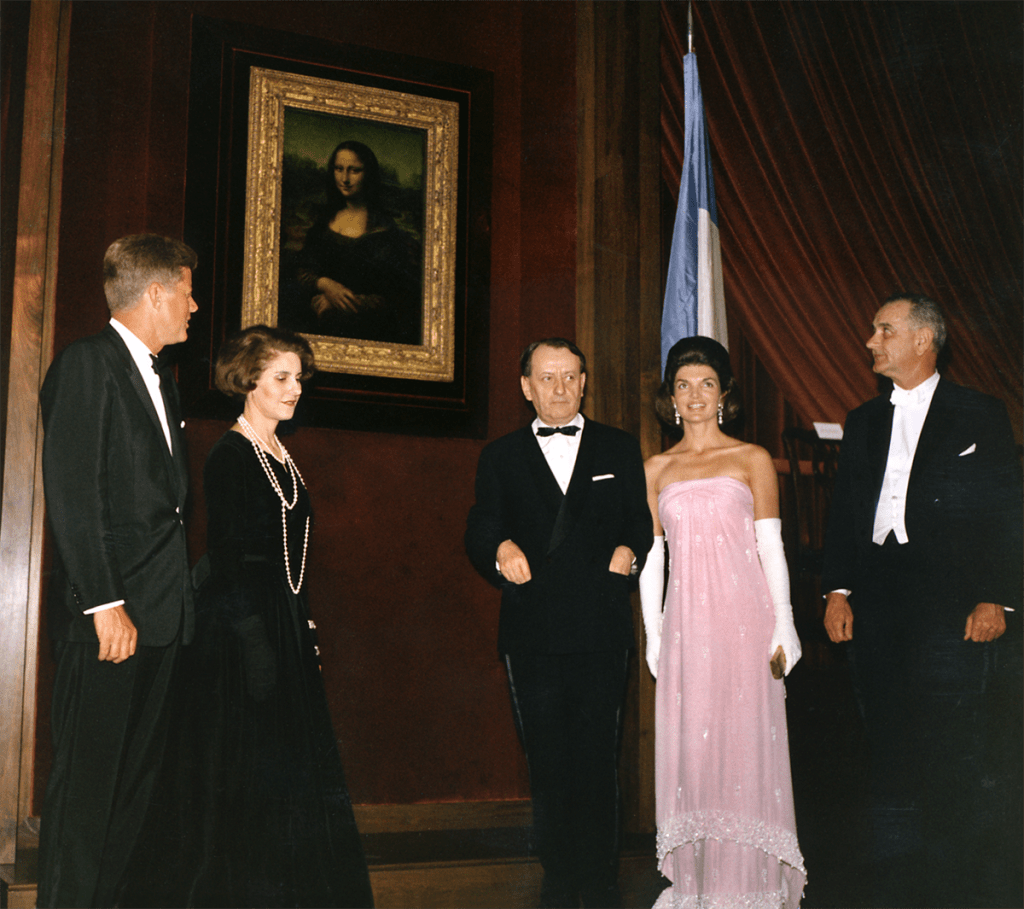 Group of five people standing in front of the Mona Lisa, all dressed in formal gala attire